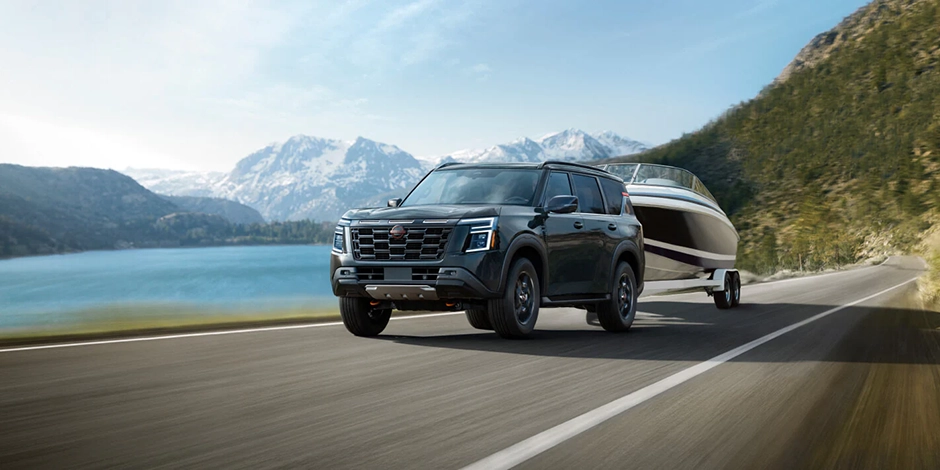 Nissan SUV towing a boat beside a mountain lake