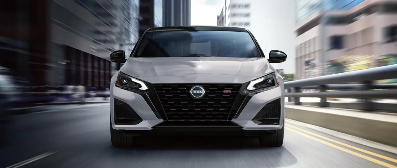 Silver Nissan sedan driving through a city