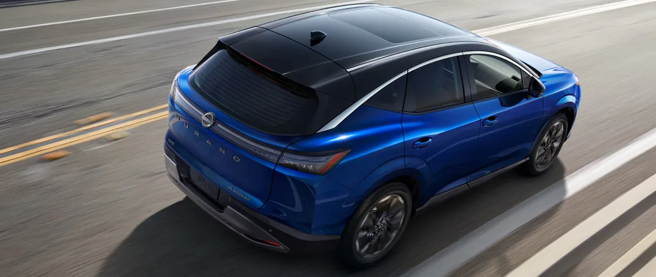Blue Nissan crossover driving on a road
