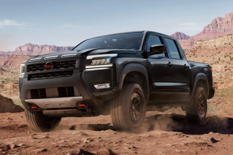 Dark Nissan pickup truck driving over desert terrain