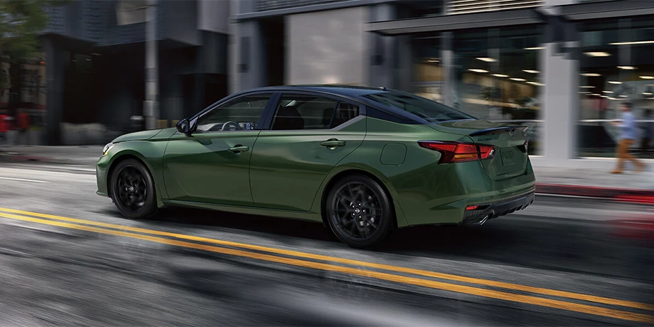 Green Nissan sedan driving through a city