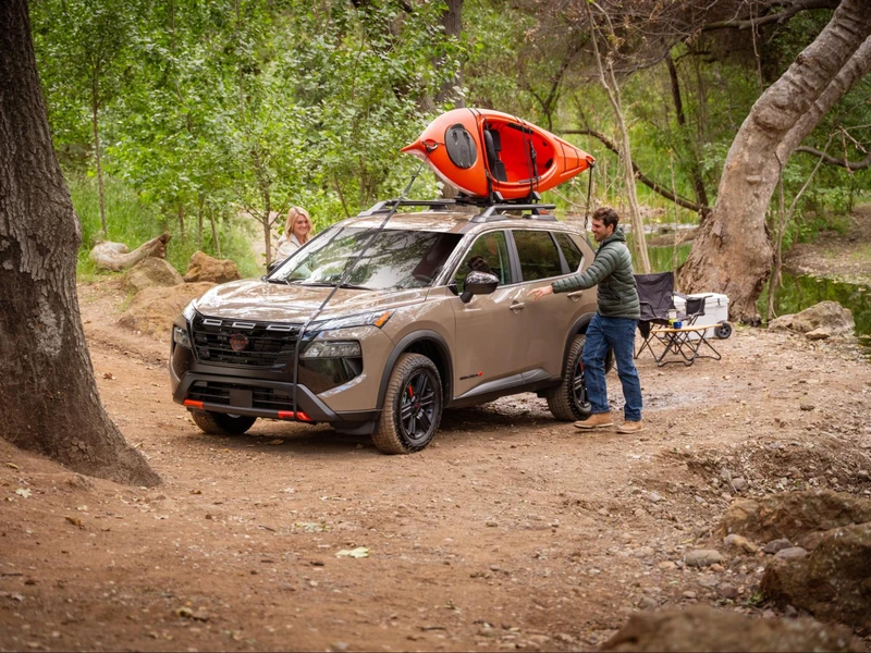Nissan SUV with outdoor gear in a wooded landscape
