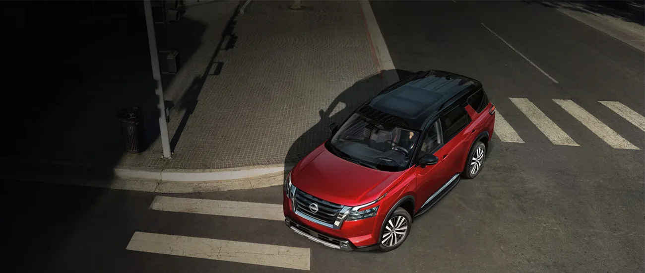 Red Nissan SUV viewed from above on a city street