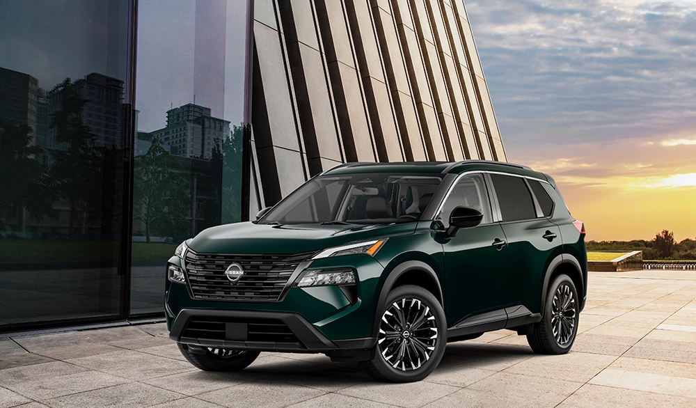 Green Nissan Rogue beside a modern building at sunset