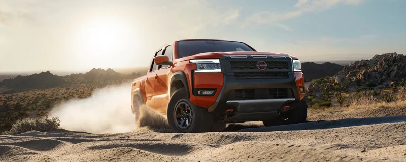 Orange Nissan Frontier driving through a desert landscape