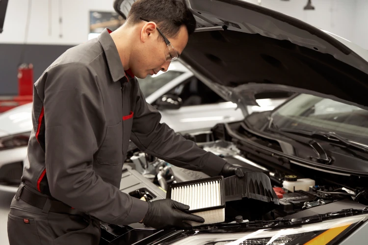 Nissan service technician working under the hood of a vehicle