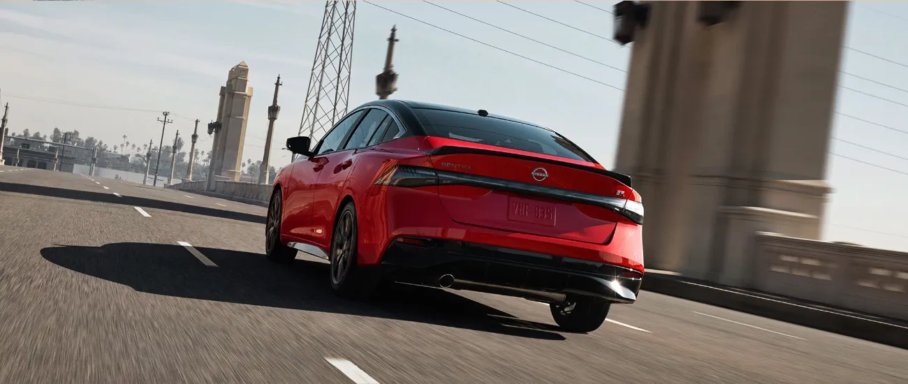 Red Nissan Altima driving on a city highway