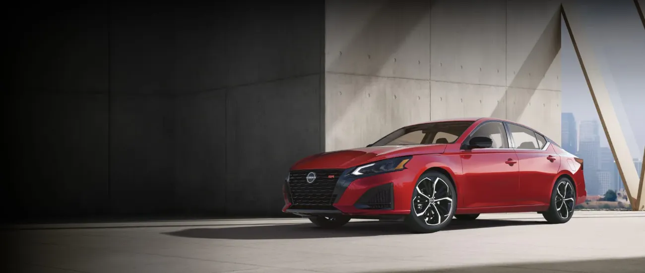 Red Nissan Altima parked in a modern concrete space