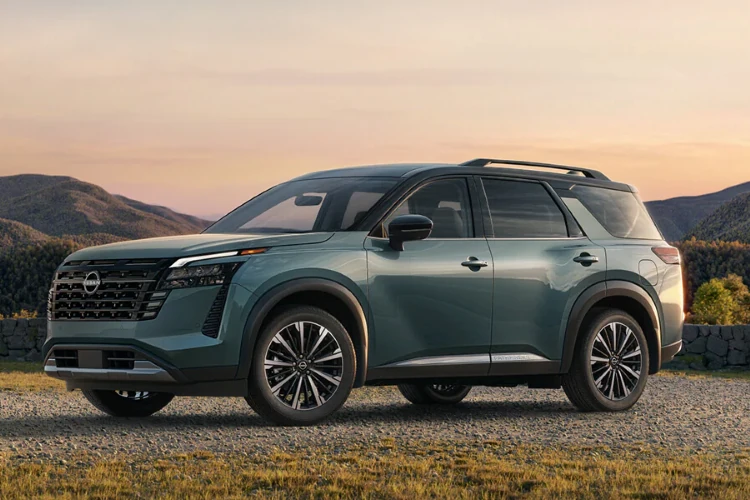 Green Nissan SUV parked in a landscape at sunset