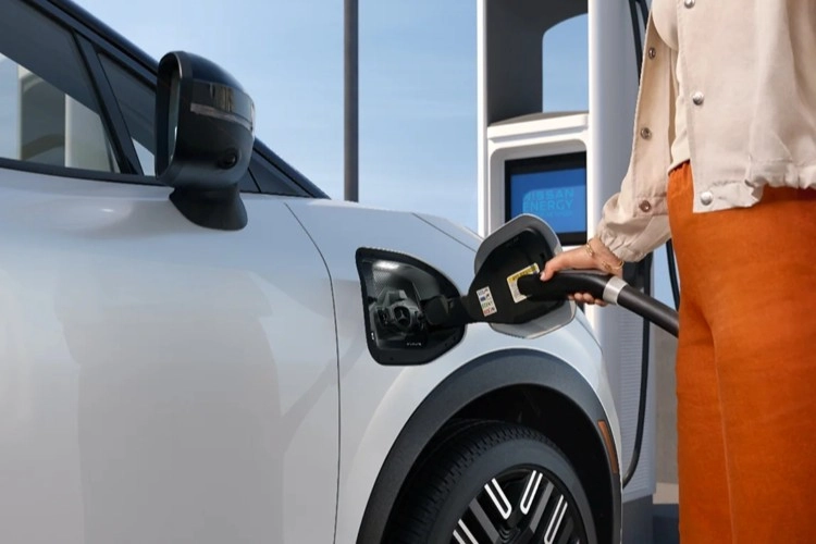 Person connecting a fast-charging cable to the passenger-side port of a Nissan LEAF