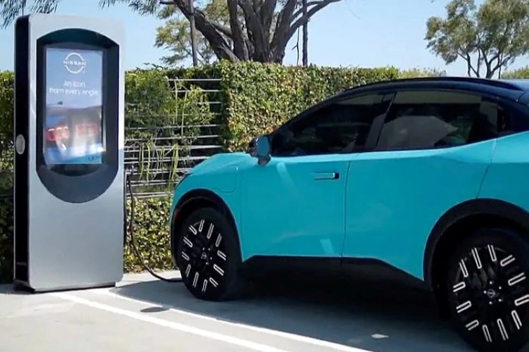 Teal Nissan LEAF parked beside a public charging kiosk