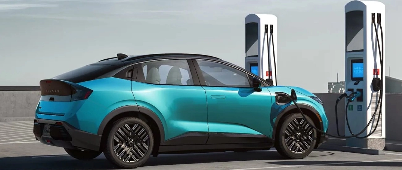 Teal Nissan LEAF plugged in at a public charging station