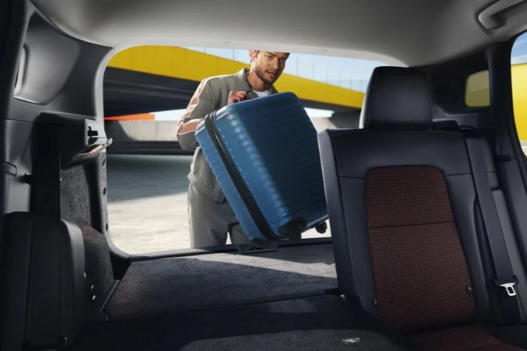 Suitcase being loaded into the rear cargo area of a Nissan Kicks