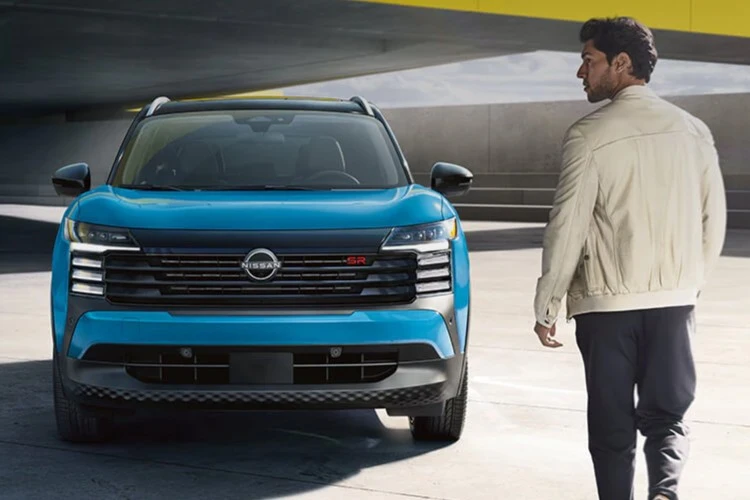 Person walking toward a blue Nissan Kicks in a parking structure