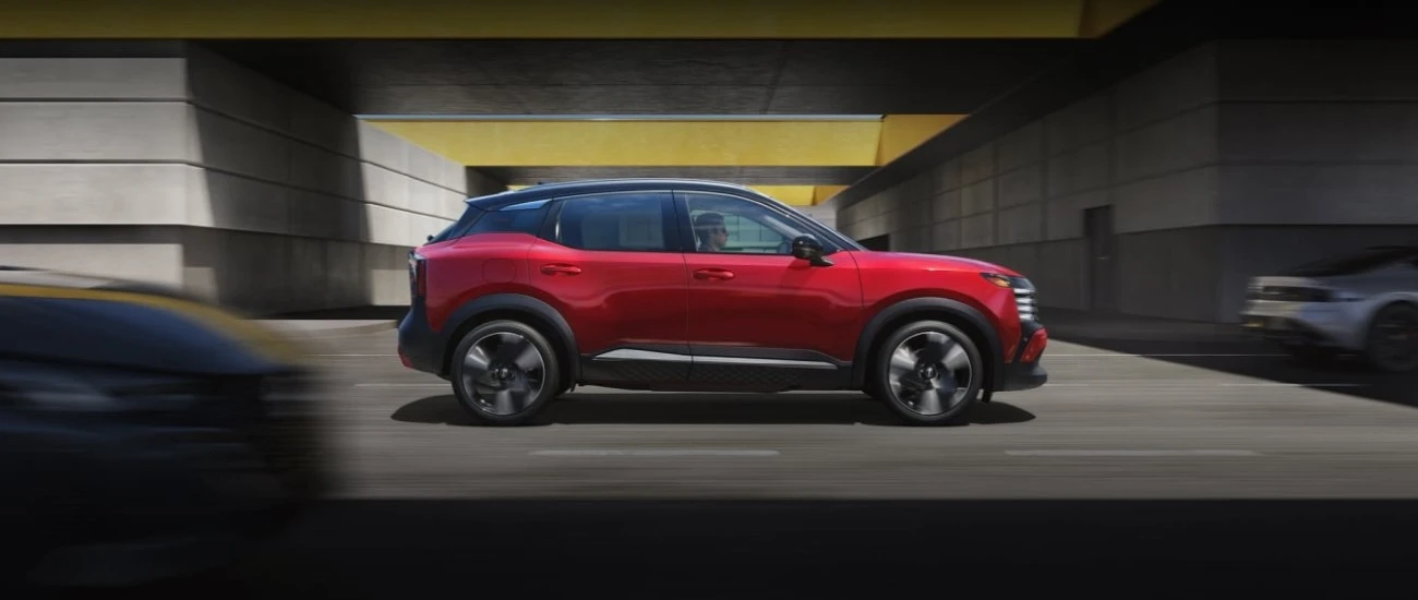 Red Nissan Kicks parked in a city underpass, shown in profile