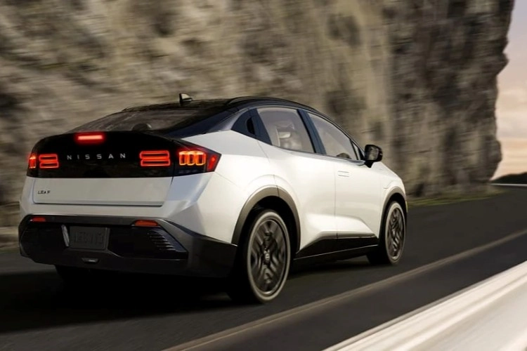 White Nissan LEAF on a coastal road, seen from the rear three-quarter angle
