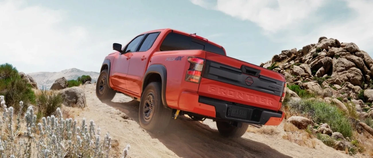 Red Nissan Frontier PRO-4X climbing a rocky desert trail