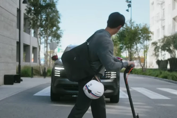 Pedestrian with a scooter stepping into a crosswalk in front of a vehicle