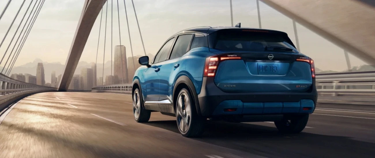 Blue Nissan Kicks crossing a suspension bridge, seen from the rear three-quarter angle
