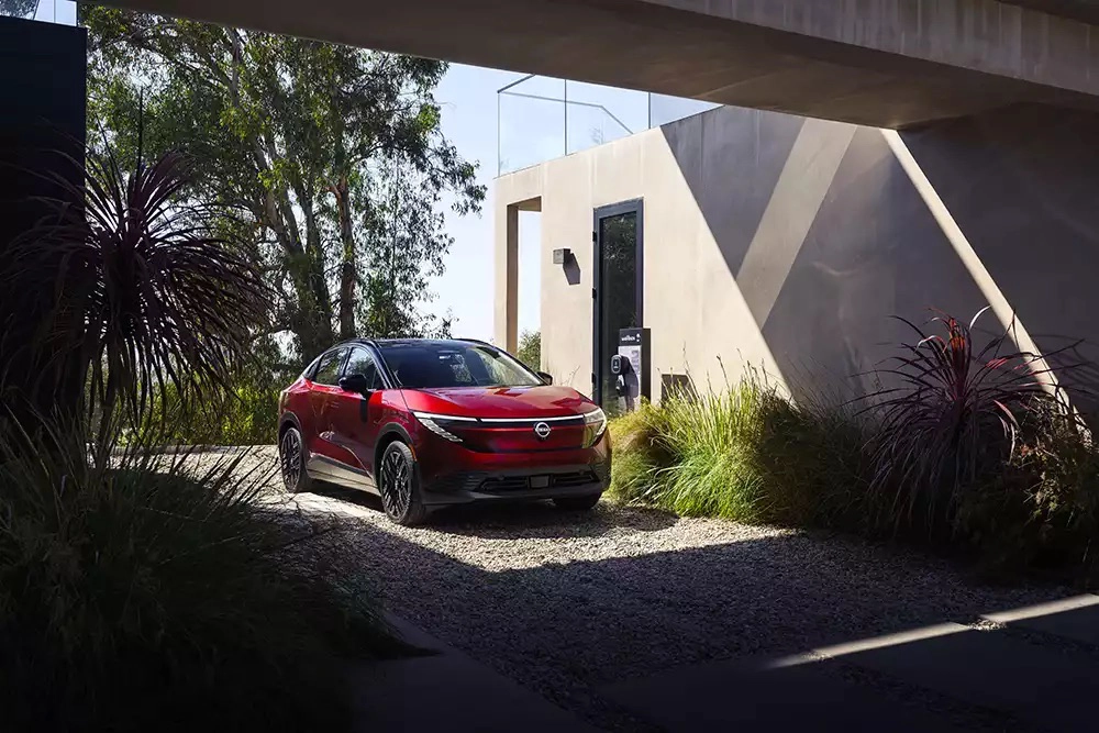 Red Nissan Ariya parked beside a home