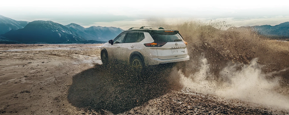 Nissan SUV driving through a muddy mountain landscape