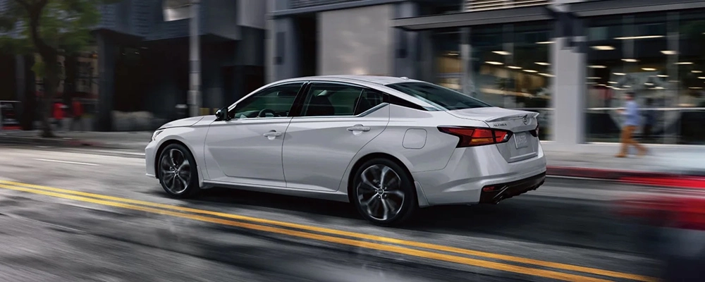 White Nissan Altima driving on a city street