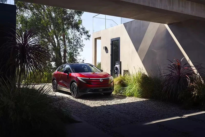 Red Nissan crossover parked beside a modern home