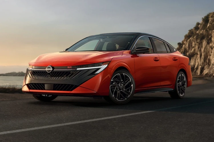 Orange Nissan sedan driving along a coastal road