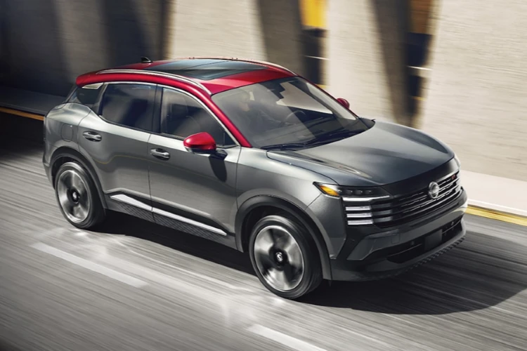 Gray Nissan SUV with a red roof driving on a city road