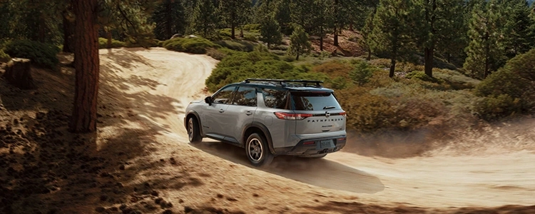 Back Three-Quarters of Silver 2025 Nissan Pathfinder® Driving on a Dirt Road
